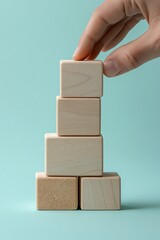 A hand carefully placing a wooden block on top of a stack, symbolizing growth and creativity in play.
