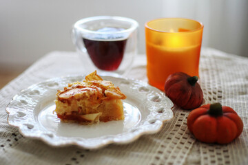 Pumpkin pie on a plate, cup of tea, candle. Autumn mood