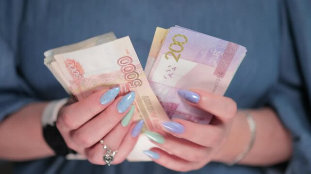 Female hands holding paper bills of Russian rubles and Belarusian rubles