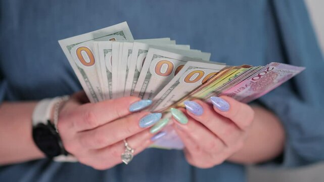 Female hands holding paper bills of US dollars and Belarusian rubles