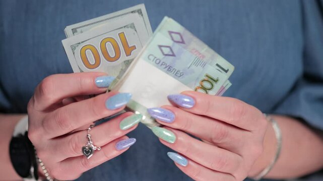 Female hands holding paper bills of US dollars and Belarusian rubles