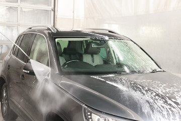 Washing auto with high pressure water jet at car wash, closeup