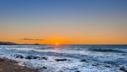 Stunning Sunset Over the Ocean Waves With Rocky Shoreline During Evening on a Clear Day