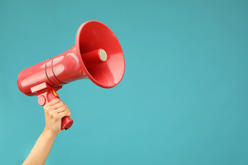Woman holding megaphone speaker on blue background, closeup. Space for text