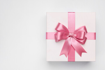 Gift box with pink bow on light grey background, top view. Space for text