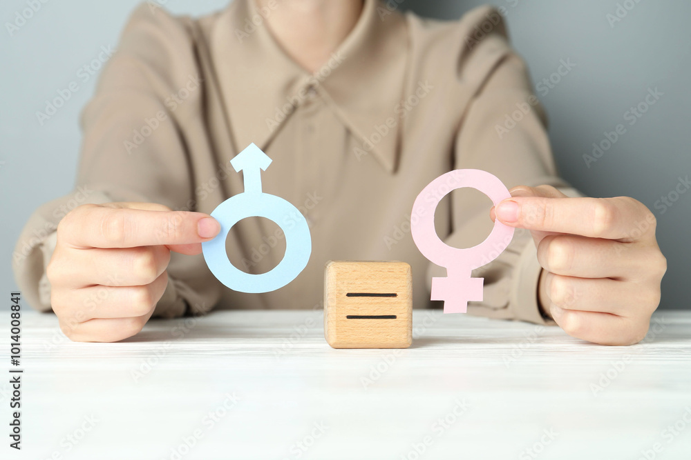 Wall mural Gender equality concept. Woman with male and female symbols at white table, closeup