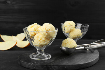 Scoops of melon sorbet in glass dessert bowls on dark wooden table