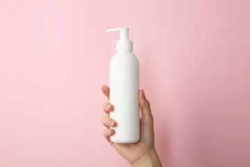 Woman with shampoo bottle on pink background, closeup