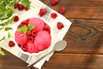 Delicious raspberry sorbet in bowl, fresh berries, mint and spoon on wooden table, flat lay. Space for text