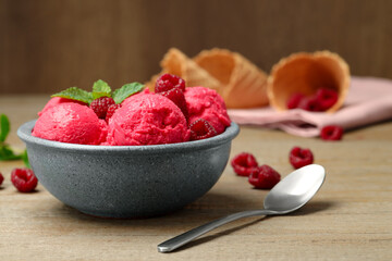 Delicious raspberry sorbet with fresh berries in bowl and spoon on wooden table