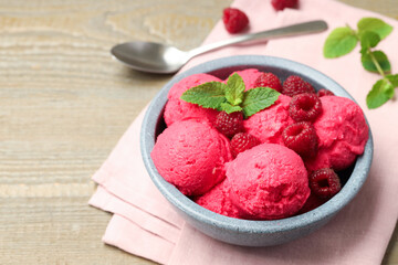 Delicious raspberry sorbet with fresh berries in bowl and spoon on wooden table, closeup