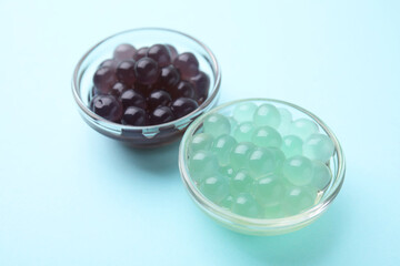 Color tapioca pearls in bowls on light blue background, closeup