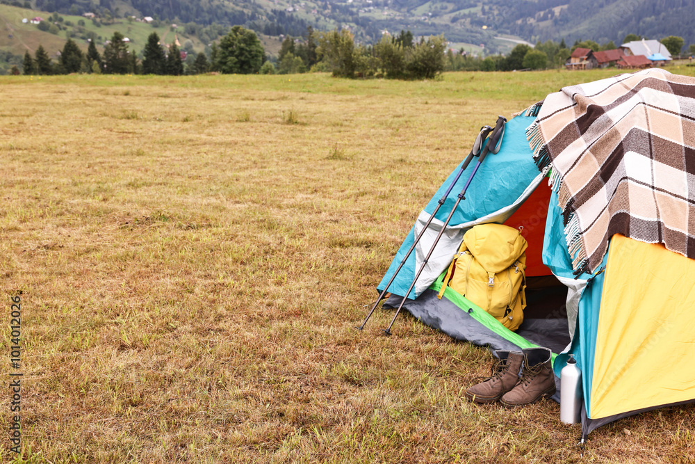 Wall mural Camping tent and tourist stuff on grass in mountains, space for text