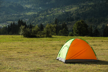 Tent on green grass in mountains, space for text