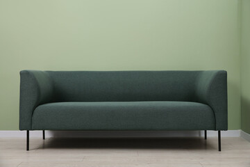 One stylish sofa near green wall indoors