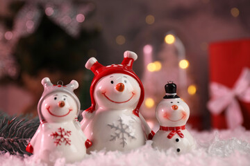 Funny snowmen figures and fir branch on artificial snow, closeup