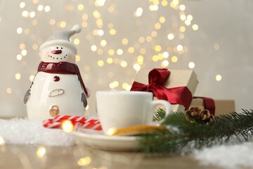 Funny snowman figure and other decor on table against blurred lights