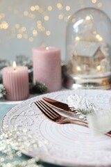 Christmas place setting with plate, cutlery and festive decor on table, closeup