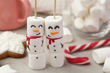 Obraz premium Funny snowmen made of marshmallows and other sweets on light table, closeup