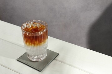 Refreshing espresso tonic drink on white wooden table, space for text