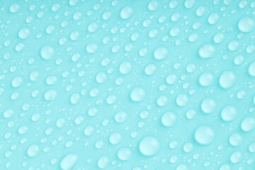 Water drops on turquoise background, top view