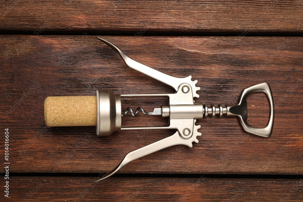 Sticker Wing corkscrew and cork on wooden table, top view