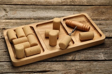 Corkscrew, tray and corks on wooden table
