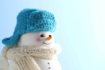 Cute decorative snowman against light blue background, closeup. Space for text