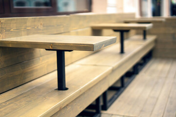 wooden tables seamlessly integrated into a long bench at an outdoor restaurant, creating a...