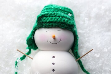 Cute decorative snowman on artificial snow, top view