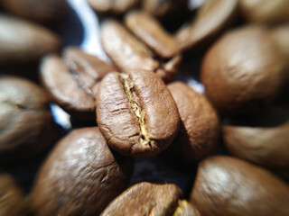 coffee grains close-up in the rays of light on a wooden surface. Ingredient for the preparation of a fragrant invigorating drink. roasted coffee beans on wooden background