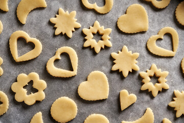 Shapes made of raw pastry dough on a sheet of baking paper - preparation of traditional Linzer Christmas cookies