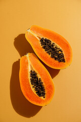 fresh, ripe papaya sliced ​​open on orange background, harsh sunlight