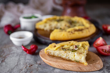 A piece of potato pie on a plate on a gray background. Vegetable pie on a plate on a gray...