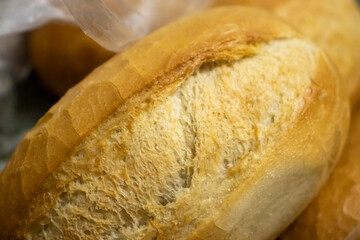 Close-up of a freshly baked bread roll, showcasing its golden crust and soft texture. Perfect for bakery and food-related concepts.