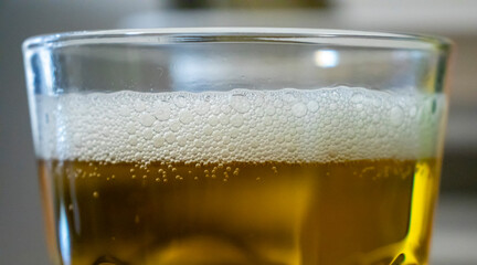 Close-up of a refreshing glass of beer with bubbles and foam, showcasing a golden liquid. Perfect for beverage-related concepts and summer enjoyment.