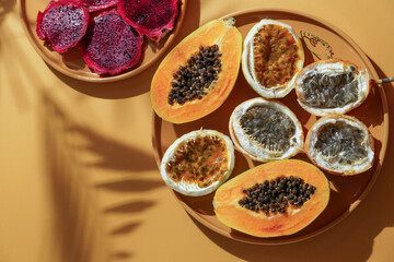 exotic tropical fruits,  passion fruits and dragon fruit, ripe papayas. on a bamboo tray with green leaves, stone background