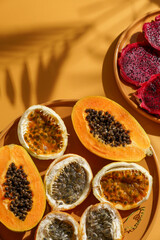 exotic tropical fruits,  passion fruits and dragon fruit, ripe papayas. on a bamboo tray with green leaves, stone background