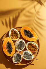 exotic tropical fruits,  passion fruits and dragon fruit, ripe papayas. on a bamboo tray with green leaves, stone background