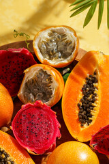 exotic tropical fruits,  passion fruits and dragon fruit, ripe papayas. on a bamboo tray with green leaves, stone background