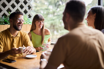 Young people relaxing on coffee break and communicating in a café.