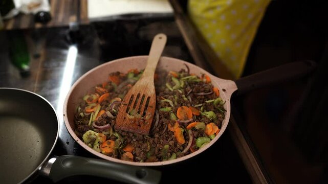 Minced meat with vegetables is stewed in a frying pan on the stove with steam. High quality 4k footage