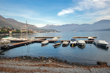 A peaceful view of boats docked at a marina on Lake Como, Italy, surrounded by mountainous terrain...