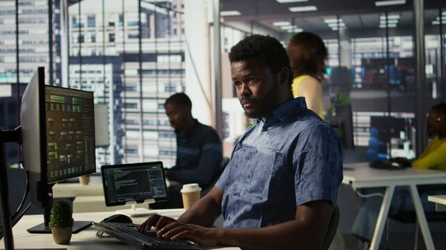 Man checking paperwork details on computer screen, solving tasks. African american bookkeeper in office making sure documents are compliant with quality assurance expectations and standards, camera B
