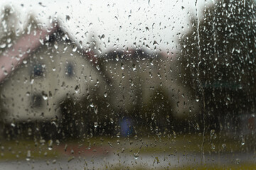 Close-up of rain droplets on a window, with a beautifully blurred background. The water droplets...