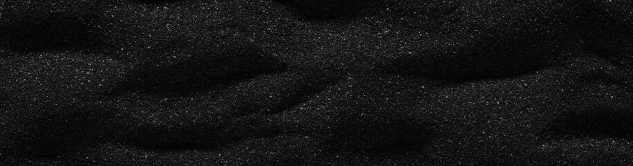Dunes of dark black sand. Stripes and ripples of smooth volcanic sand texture or wallpaper. Wave pattern in black sand background.