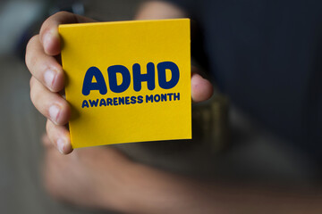 Hand holding a yellow Paper with the text ADHD Awareness Month