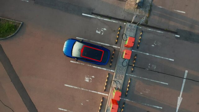 Electric car with dead battery receives electricity at public charging station. Flashing red indicator on roof shows need to receive electricity
