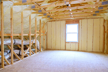 Thermal foam insulation ceiling is installed under roof of new frame house during construction