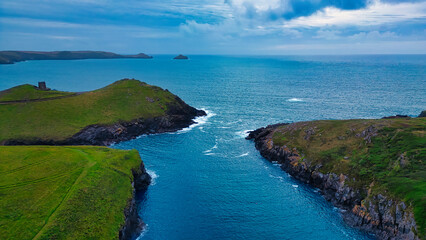 Fototapeta premium Serene Coastal Landscape with Islands and Green Hills in Tintagel, Cornwall, UK
